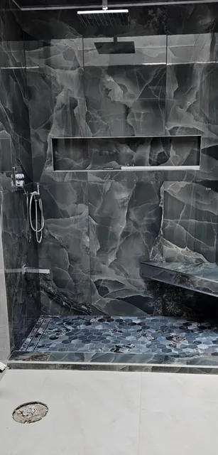 Dark stone-look walk-in shower with bench and niche